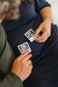 Picture of a couple holding ultrasound photos, they are expecting twins.